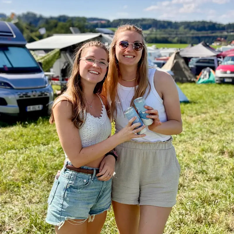 Zwei Freundinnen mit IBEX-Dosen auf einem Festival-Campingplatz